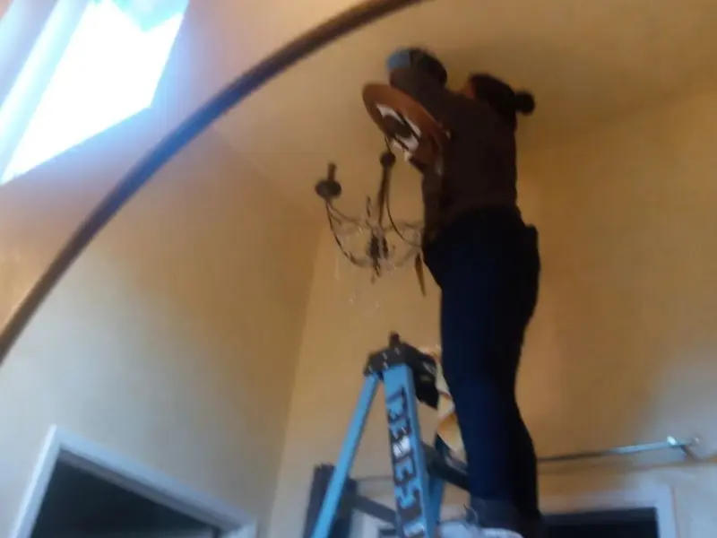Electrician installing a chandelier in a Parma residence